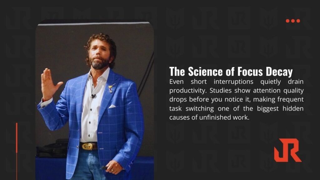 Motivational speaker Jason Redman gesturing passionately during talk on focus decay, wearing bold blue plaid suit and gold belt buckle.