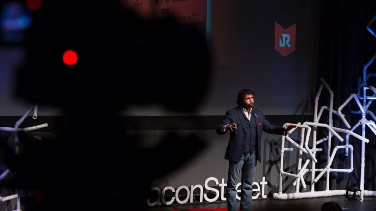 Jason Redman delivering keynote on TEDx-style stage being filmed live — how to boost employee morale at company events with what actually works.